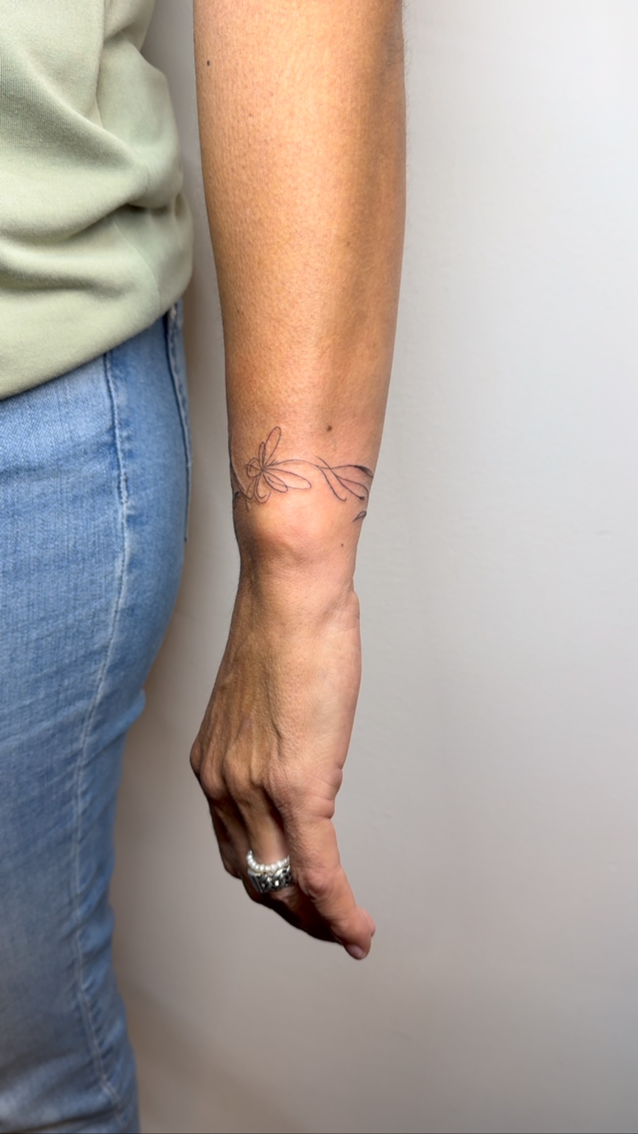 Fine-line butterfly and leaves on a forearm by Luna Fino